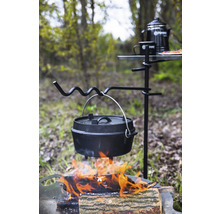 Gusseisen-Topf über offenem Feuer an einem Dreibein mit Campingtisch und Zubehör im Freien