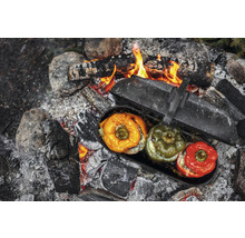 Gefüllte Paprika in einem Topf über einem Lagerfeuer.