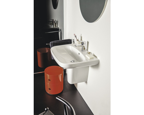 Weißes Wandwaschbecken mit Armatur und Badaccessoires in einem Badezimmer.
