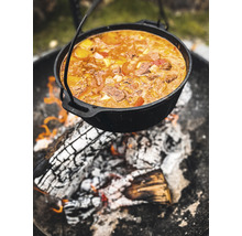 Schwarzer Dutch Oven über einem Lagerfeuer mit Essen gefüllt.