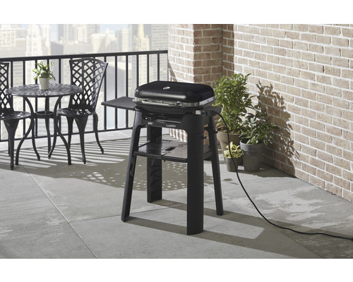 Elektrischer Grill auf einem Balkon mit Tisch und Stühlen.