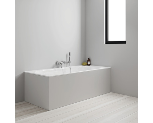 Badewanne mit Verkleidung, Armatur und Pflegeprodukten im Badezimmer.