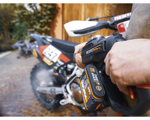 Eine Person reinigt ein Motorrad mit einem Akku-Hochdruckreiniger.