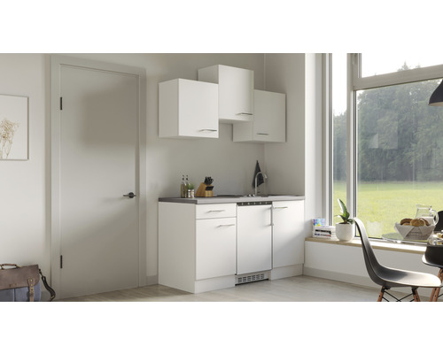 Kleine Küche mit weißen Schränken und Blick aus dem Fenster.