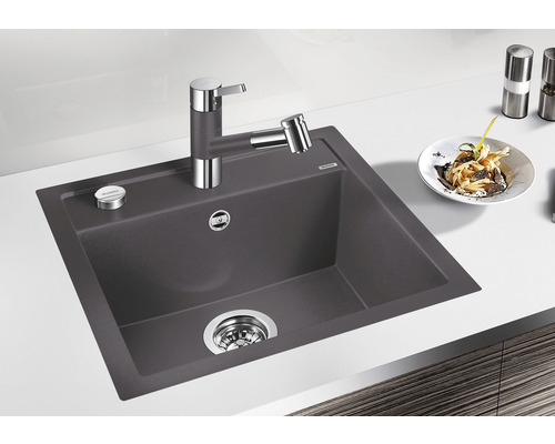 Spüle aus Granit mit Wasserhahn und Spülmittelspender auf einer Küchentheke.