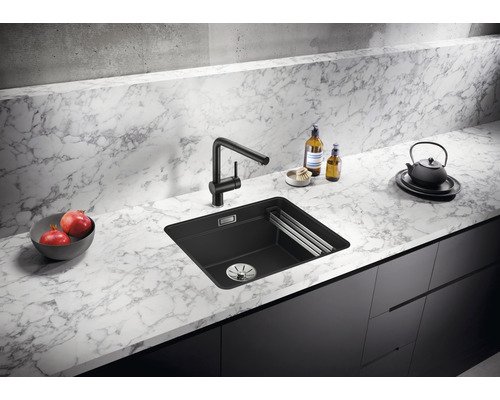 Schwarzes Spülbecken mit Wasserhahn auf Marmorarbeitsplatte in einer Küche.