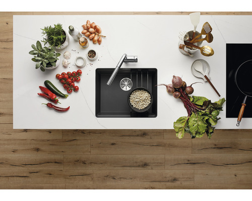 Küchenspüle mit Armatur auf einer Küchentheke mit Gemüse und Küchenutensilien