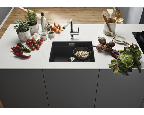 Küchenspüle aus Verbundwerkstoff mit Armatur und frischen Zutaten auf der Arbeitsplatte