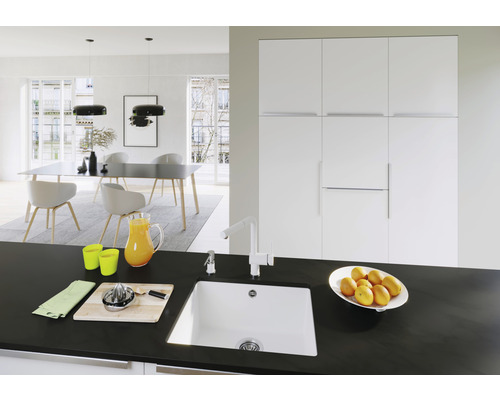 Helles Interieur mit Spüle, Armatur und Küchenutensilien auf einer Küchentheke vor einem Essbereich