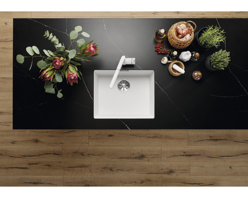 Aufnahme von oben einer Küche mit einer Spüle, Armatur, Blumen, Kräutern und Gewürzen auf einer Arbeitsplatte