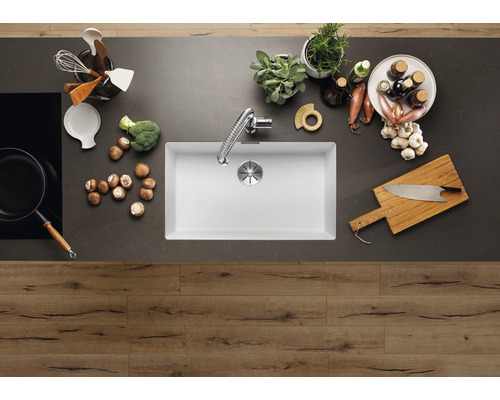 Küchenszene mit Spüle, Armatur, Kochfeld und Küchenutensilien auf einer Küchentheke