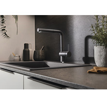 Küchenspüle mit Wasserhahn und verschiedenen Küchenutensilien auf einer Arbeitsplatte