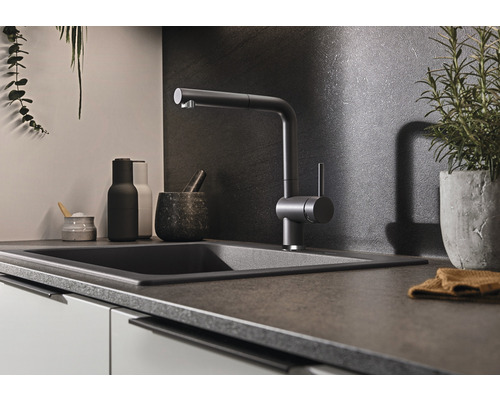 Küchenspüle mit Wasserhahn und verschiedenen Küchenutensilien auf einer Arbeitsplatte