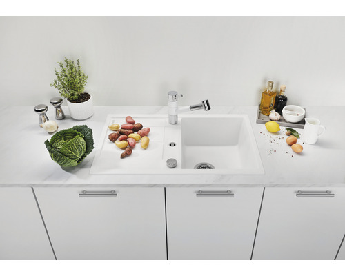 Küchenspüle mit Abtropffläche und Armatur auf einem weißen Unterschrank mit Gemüsesorten