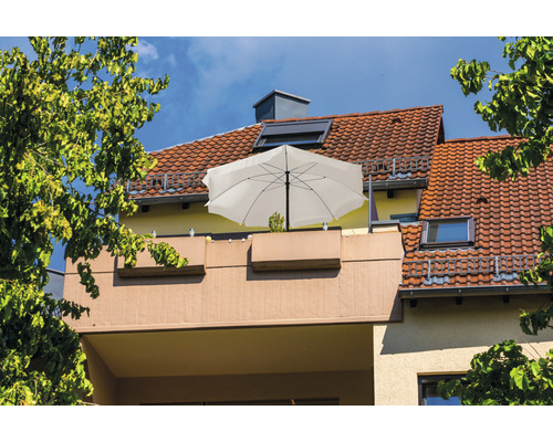 Balkon mit Sonnenschirm und Bepflanzung vor einem Haus