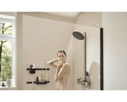 Dusche mit Duschabtrennung, Kopfbrause und Wandregalen in einem hellen Badezimmer.