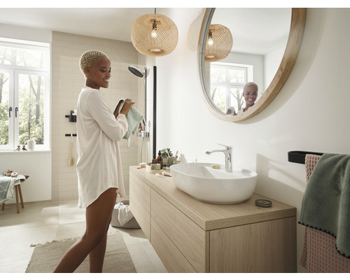 Modernes Badezimmer mit Waschtisch, rundem Spiegel und natürlicher Beleuchtung