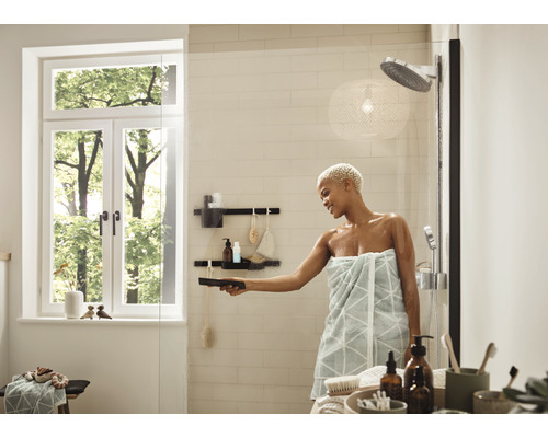 Helles Badezimmer mit Dusche, Fenster und Frau, die eine Glasduschwand mit einem Abzieher reinigt