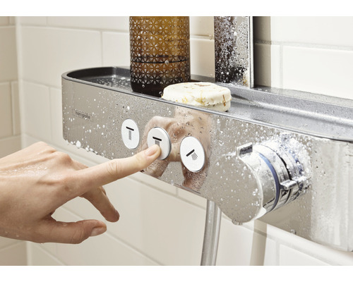 Duscharmatur mit Ablagefläche im Badezimmer, eine Hand bedient die Tasten