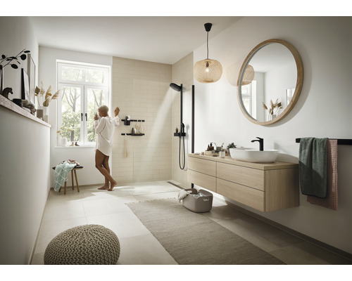 Helles Badezimmer mit Dusche, Waschtisch, Spiegel und Dekorationen für ein modernes Ambiente.