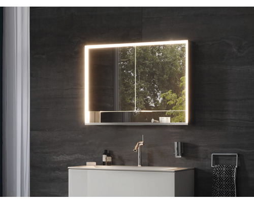 Modernes Badezimmer mit beleuchtetem Spiegelschrank, Waschtisch und Armatur.