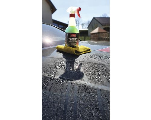 Reinigungsmittel und Tuch auf einer Motorhaube