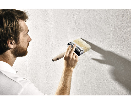 Mann streicht Wand mit Quast