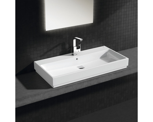 Rechteckiges Keramikwaschbecken mit Armatur und Spiegel an dunkler Wand