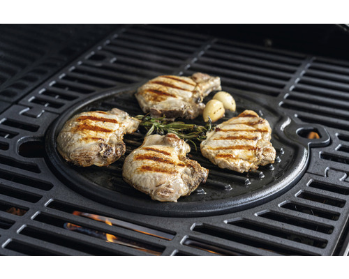 Schweinekoteletts und Knoblauch auf einem Grill zubereitet