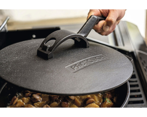 Gusseisendeckel auf einem Topf mit Speisen, gehalten von einer Hand