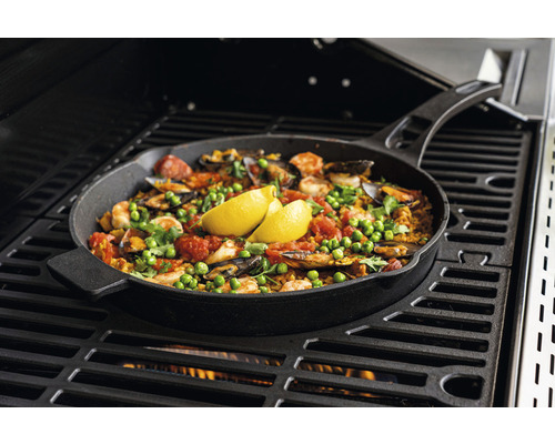 Paella in einer Bratpfanne auf einem Grill zubereitet