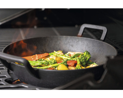 Gemüsewok auf einem Grill mit offener Flamme