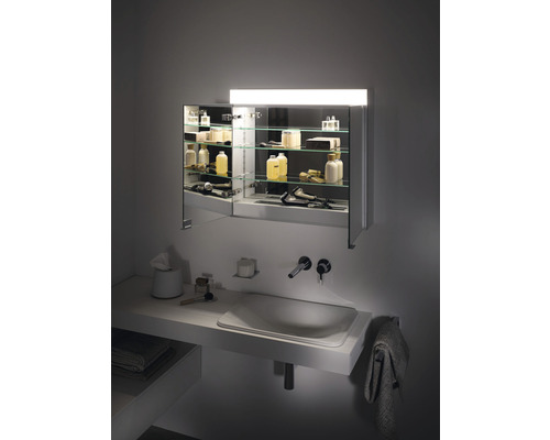 Badezimmer mit Waschbecken, Armatur und beleuchtetem Spiegelschrank mit Glasregalen