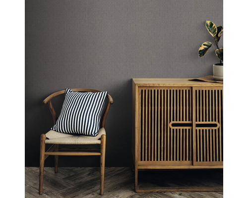 Einrichtungsbeispiel mit einer grauen Strukturtapete, einem Holzschrank und einem Stuhl mit gestreiftem Kissen.