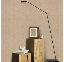 Dekoratives Zimmer mit gemusterter Tapete, Stehlampe, Bilderrahmen und dekorativen Objekten