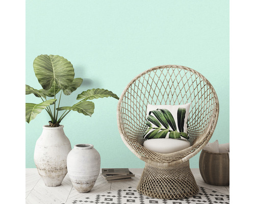 Dekorative Szene mit Korbsessel, Pflanzen in Vasen und gemustertem Teppich