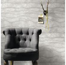 Grauer Sessel vor einer Tapete mit Wellenmuster, darüber ein Geweih