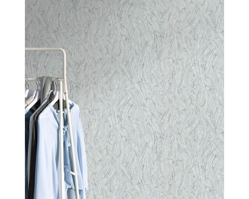 Nahaufnahme einer strukturierten Tapete mit Kleiderständer und Kleidungsstücken im Raum