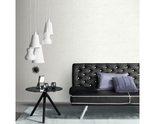 Innenaufnahme eines Zimmers mit einer schwarzen Couch mit Knöpfen, einem schwarzen Tisch, Dekorationen und mehreren weißen Lampen