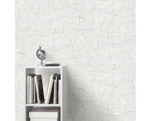 Szene mit einer weißen Tapete mit Kratzmuster und einem weißen Regal mit Dekorationsgegenständen