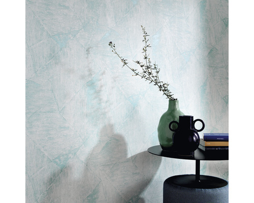 Nahaufnahme einer Wand mit Strukturtapete, einem Beistelltisch mit Dekoration und einem Hocker.