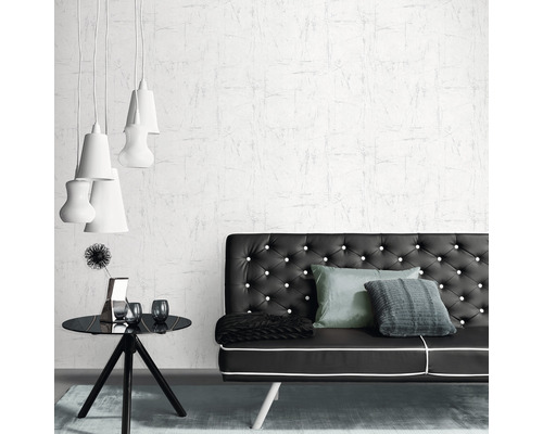 Ein Wohnzimmer mit einer schwarzen Couch, einem schwarzen Beistelltisch und einer weißen Tapete.