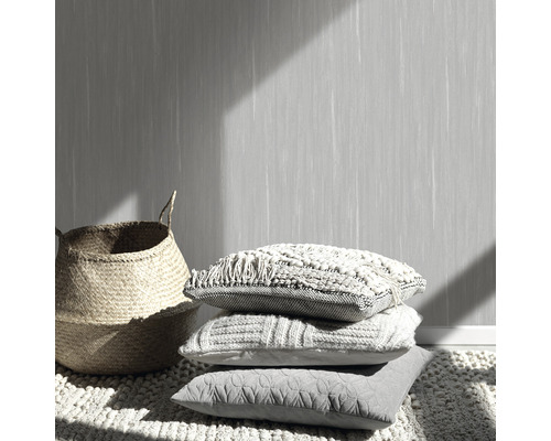 Dekorative Szene mit Kissenstapel, Weidenkorb und gemusterter Tapete