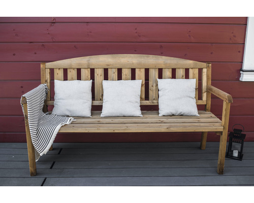 Holzbank mit drei Kissen und einer gestreiften Decke auf einer Terrasse