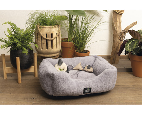 Graues Haustierbett mit Spielzeug und Pflanzen