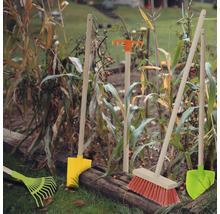 Gartenwerkzeuge wie Rechen, Besen und Schaufeln im Beet