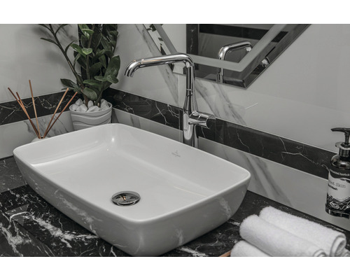 Badezimmerwaschbecken mit Armatur, Handtüchern und Dekoration auf einer Marmoroberfläche