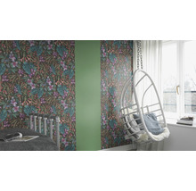 Dekoriertes Zimmer mit Tapete mit Blumenmuster, einem Schaukelstuhl und einem Bett.