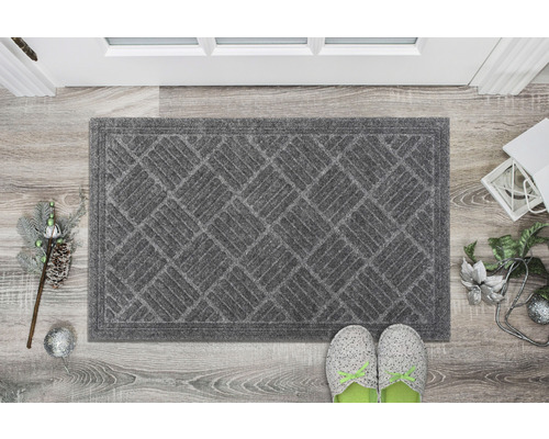 Graue Fußmatte mit geometrischem Muster vor einer Tür