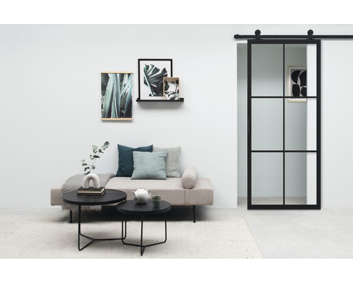 Wohnzimmer mit Sofa, Couchtischen, Wandbildern und Schiebetür